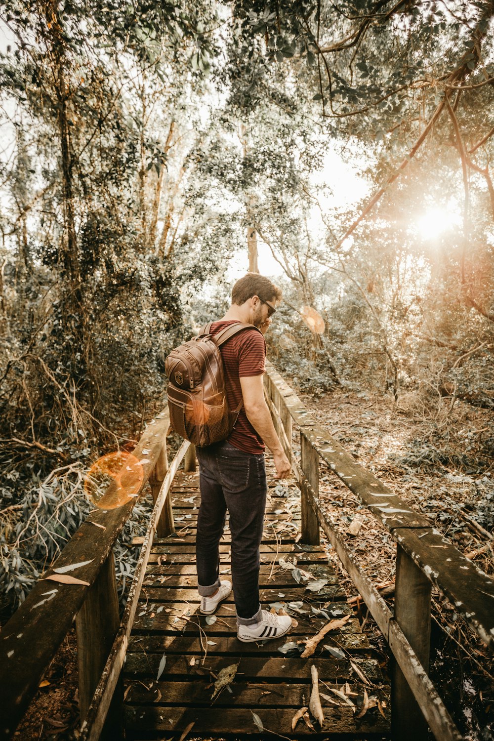 man standing on brown wooden pathway