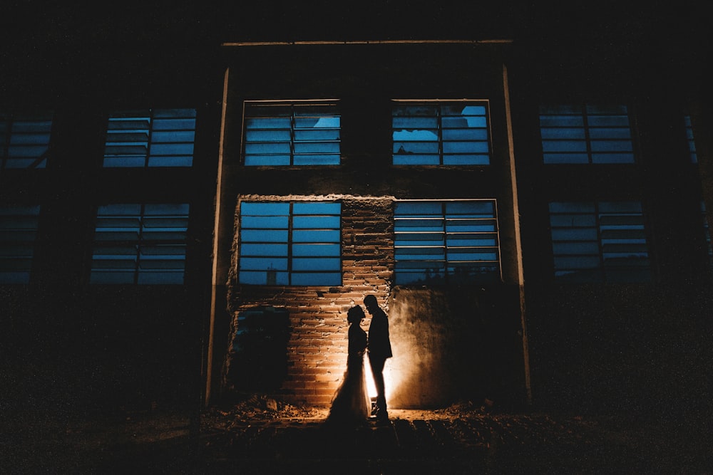 silhouette of man and woman standing beside building