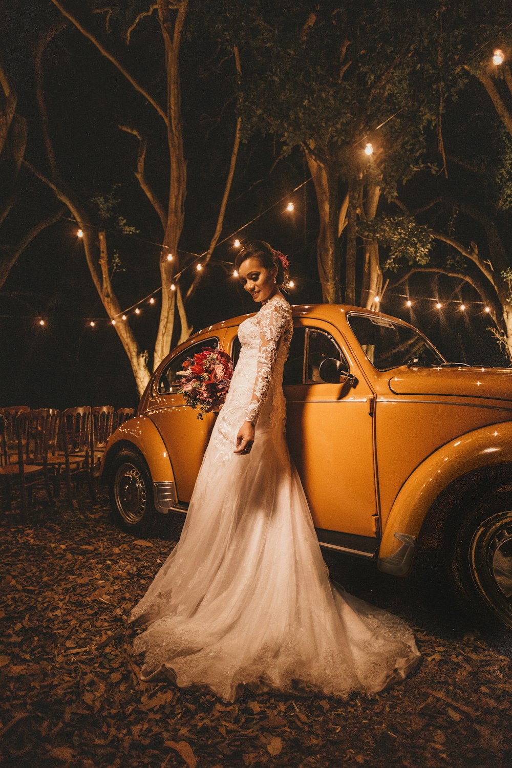 mulher no vestido de noiva branco ao lado do cupê amarelo do Volkswagen Beetle