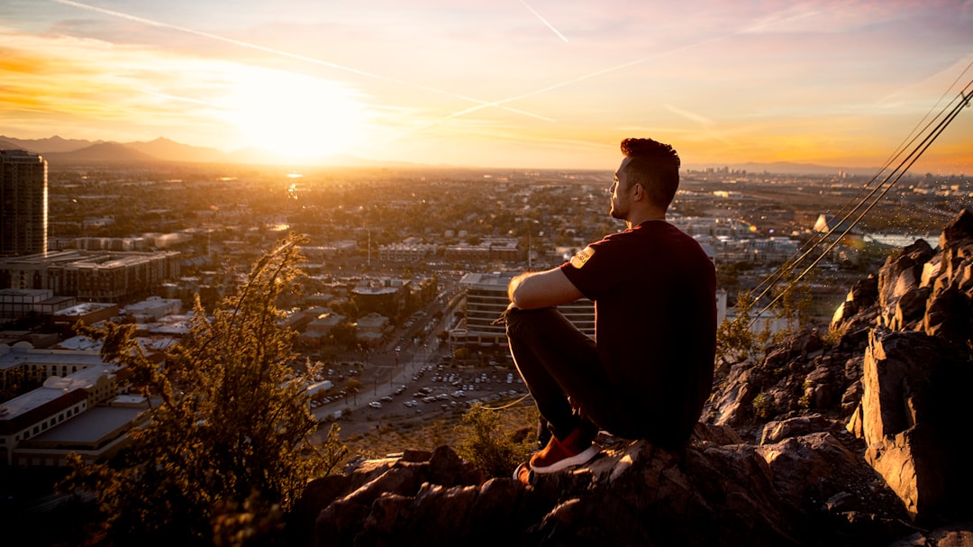 golden hour photography of man sitting on rock