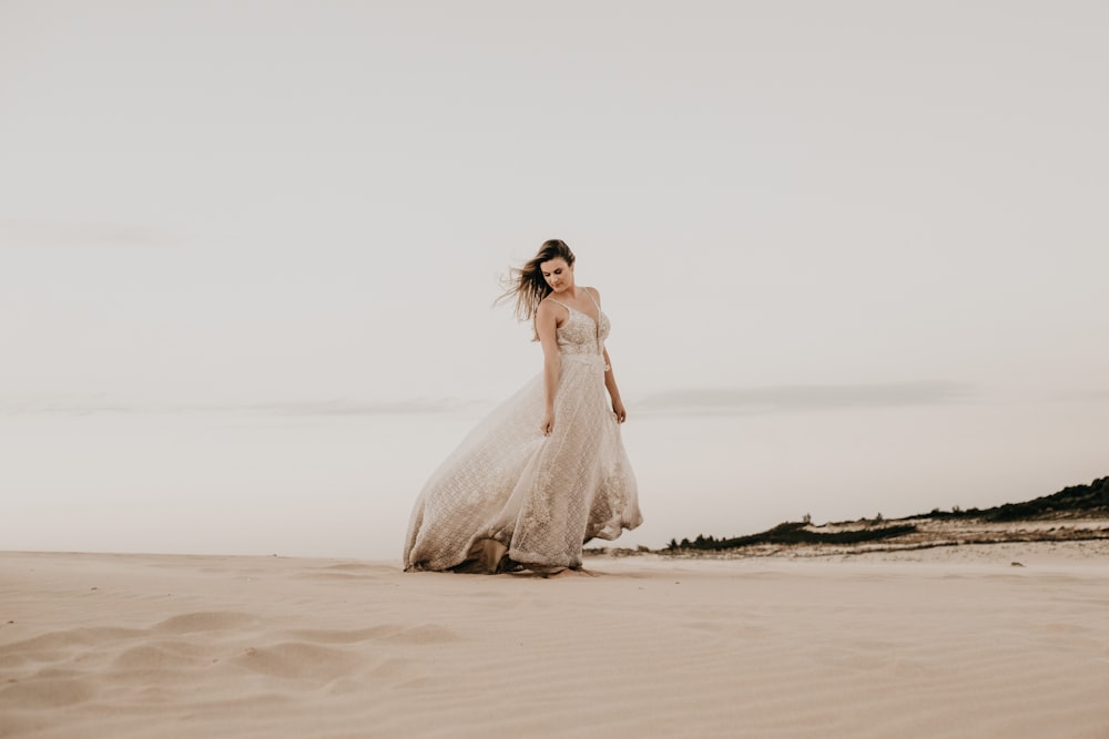 mulher vestindo vestido branco em pé na areia durante o dia