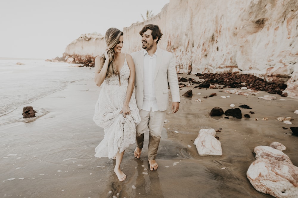 couple walking on the beach with trash during daytime