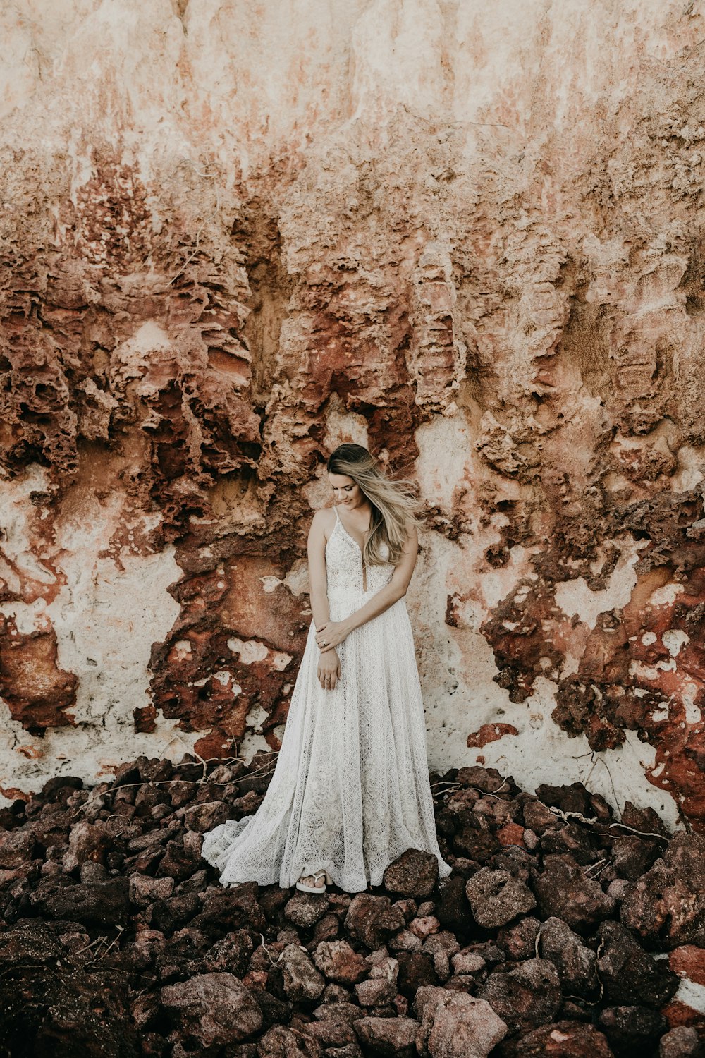 woman in white dress standing under mountain