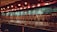 A dimly lit bar with a long wall of taps, showcasing a wide variety of beers. Above the taps, several chalkboards display the available beer selections along with their prices. The ambiance is warm and inviting, with vintage-style light fixtures providing subtle illumination.