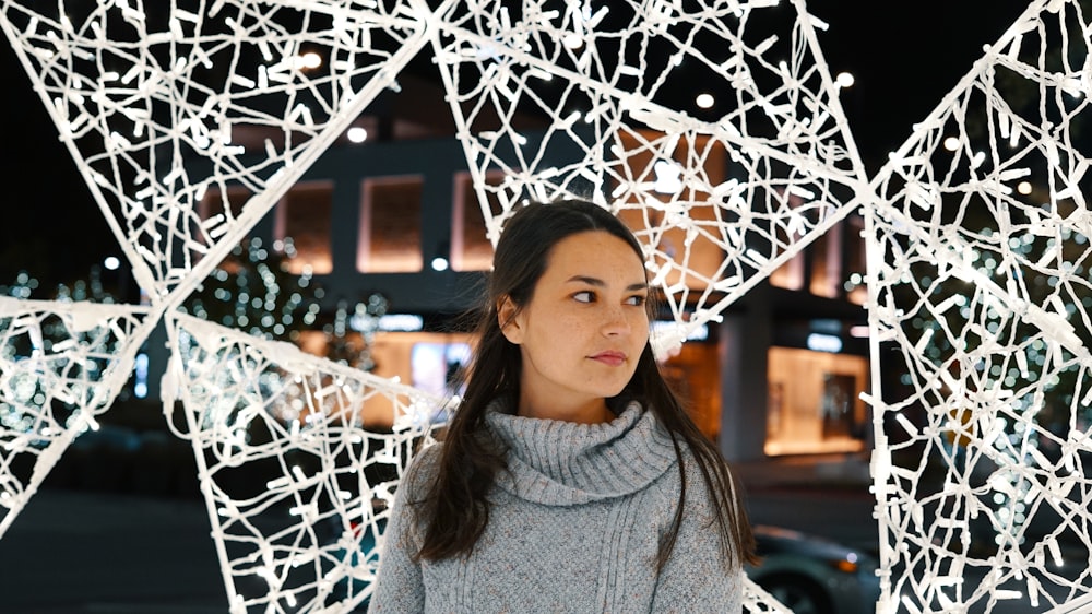 woman looking sideways under white lighted decor during night time