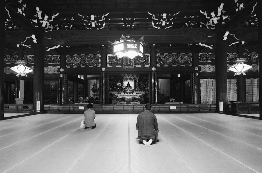 grayscale photography of two men sitting on floor front of altar