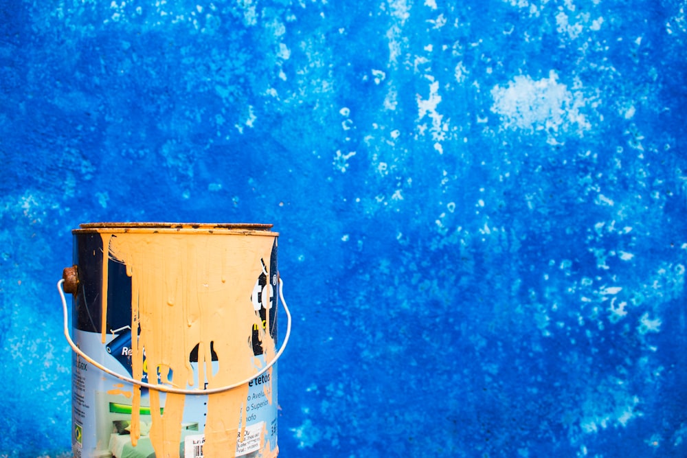 yellow paint can beside blue wall