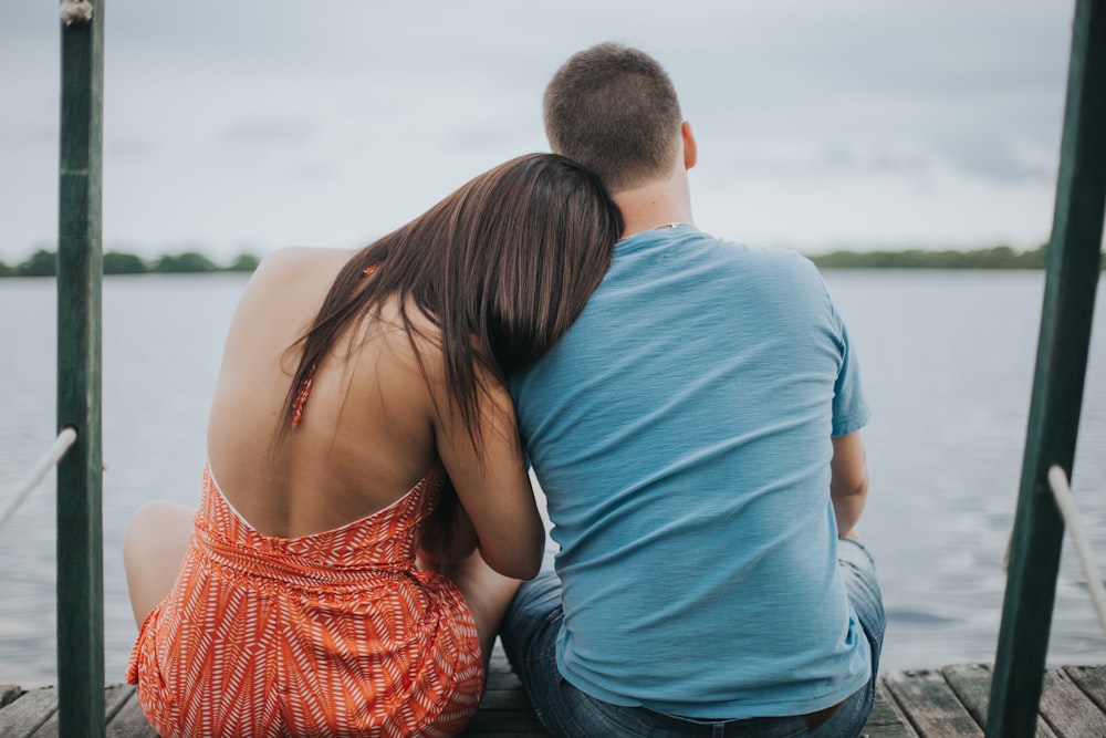 man and woman sitting on dock viewing calm sea