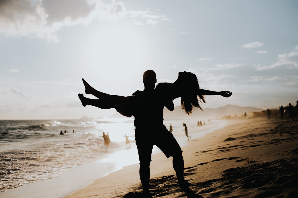 man lifting woman near ocean
