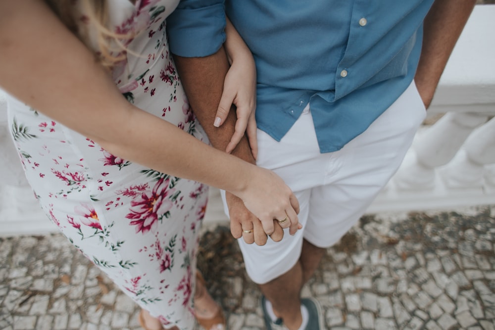 woman holding hands with man while leaning on wall