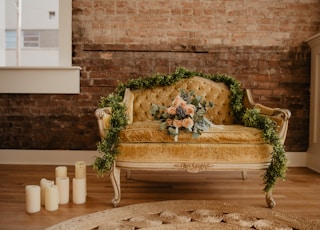 vacant tufted beige loveseat with bouquet of orange rose flowers