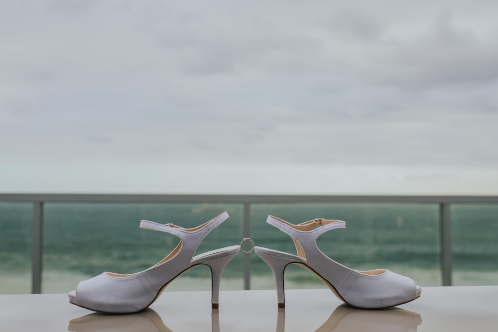 pair of grey leather strap heeled shoes on table fronting the sea