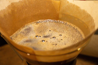Close-up photo of a steaming V60 coffee dripper with freshly brewed coffee dripping into a glass carafe.
