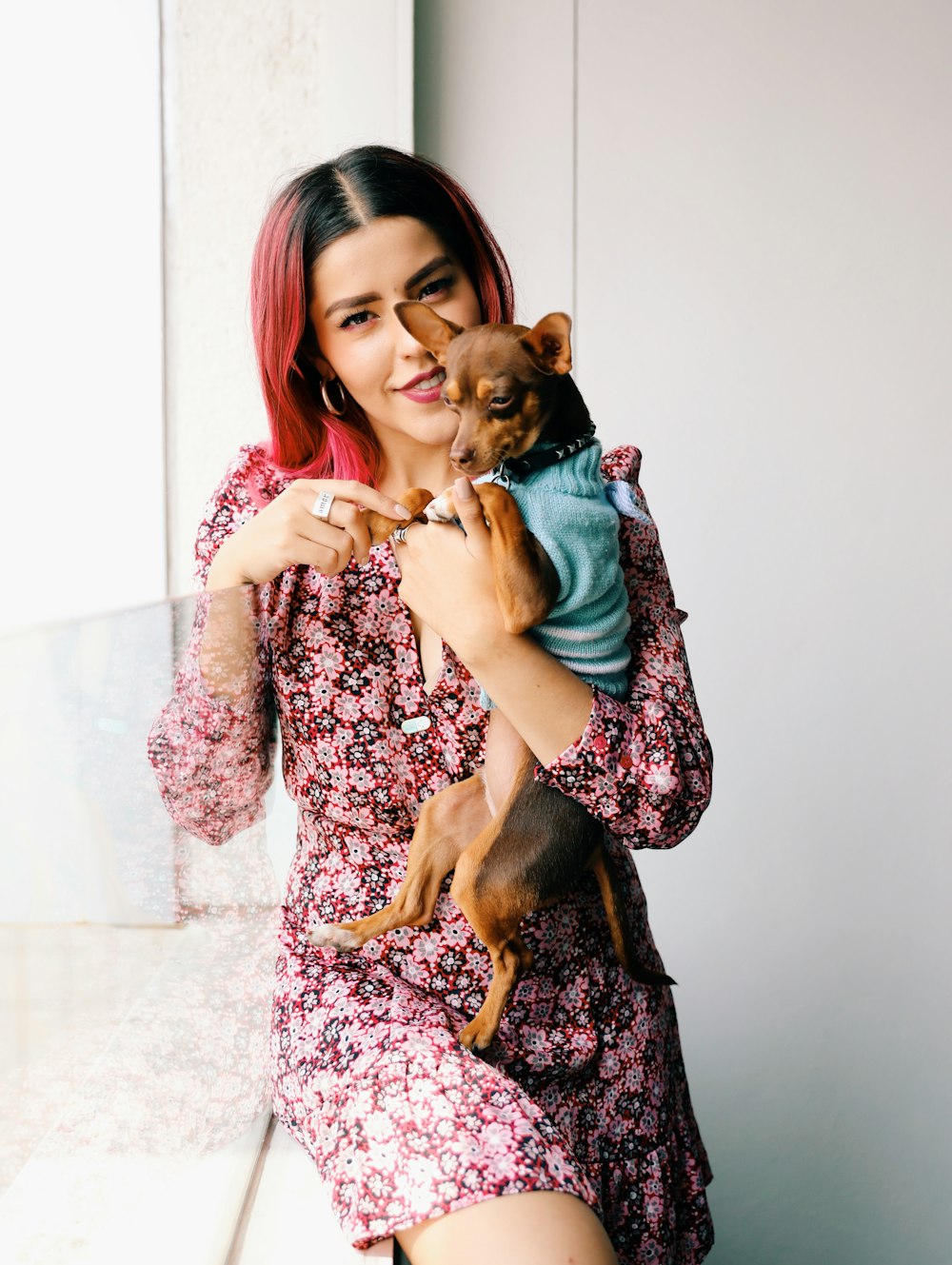 smiling woman carrying brown Chihuahua