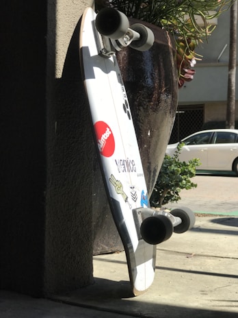 A skateboard leaning against a colorful wall, bathed in warm sunlight.