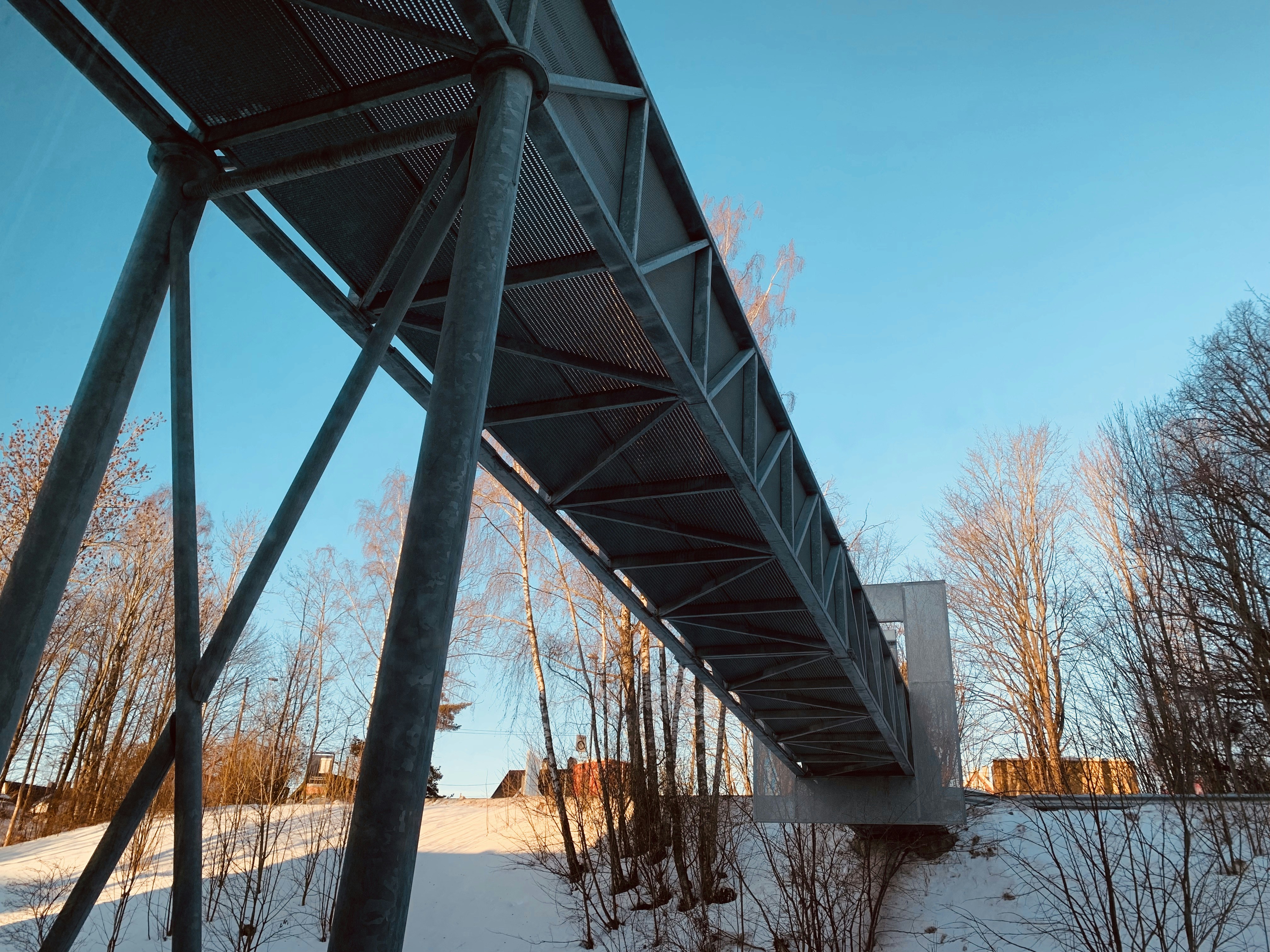 Pont métallique gris au-dessus de la neige sous un ciel bleu hivernal
