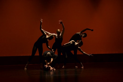 Professional dancers performing a contemporary routine on a grand stage with dramatic lighting.