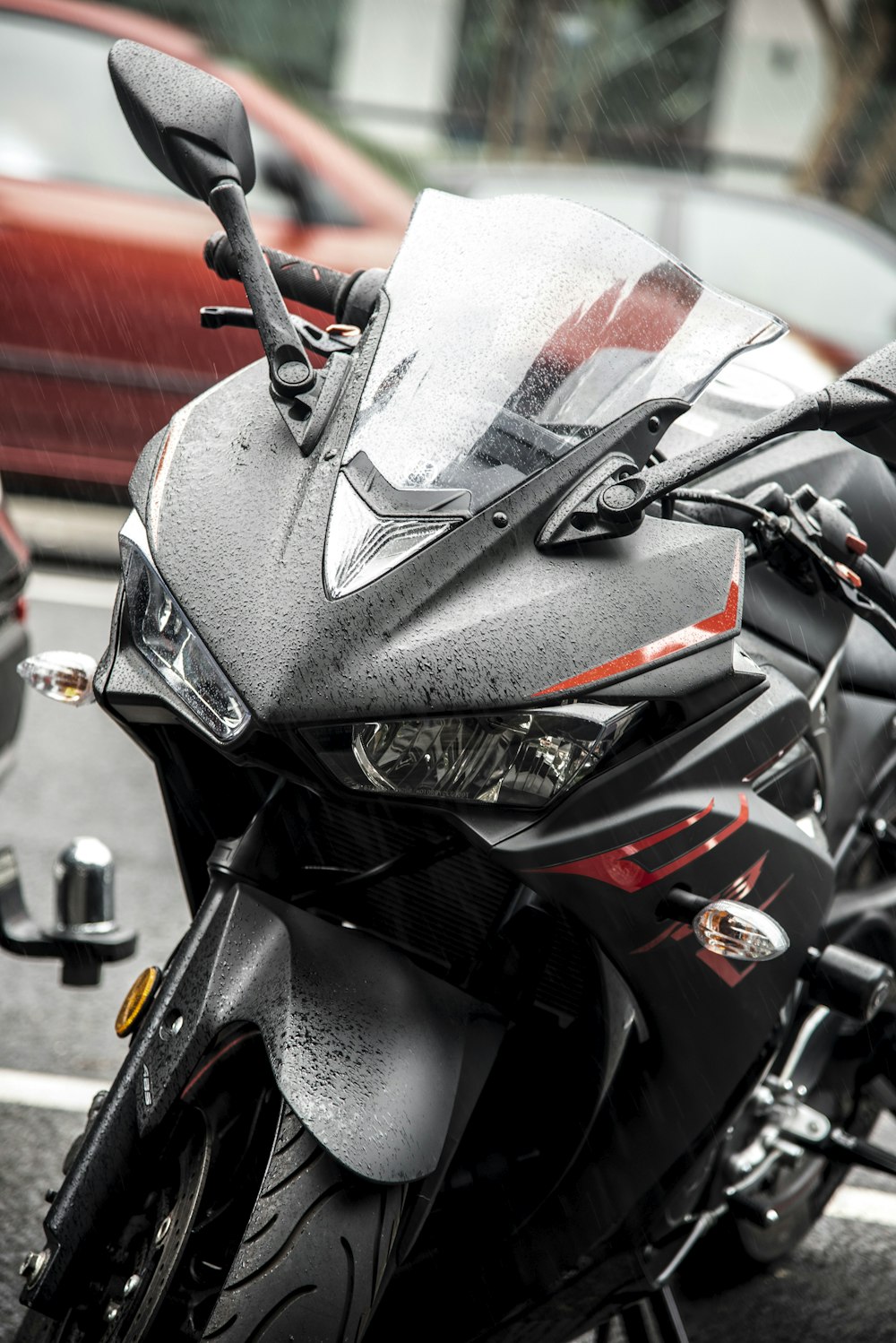 black and red Yamaha R1 sports bike near parked car