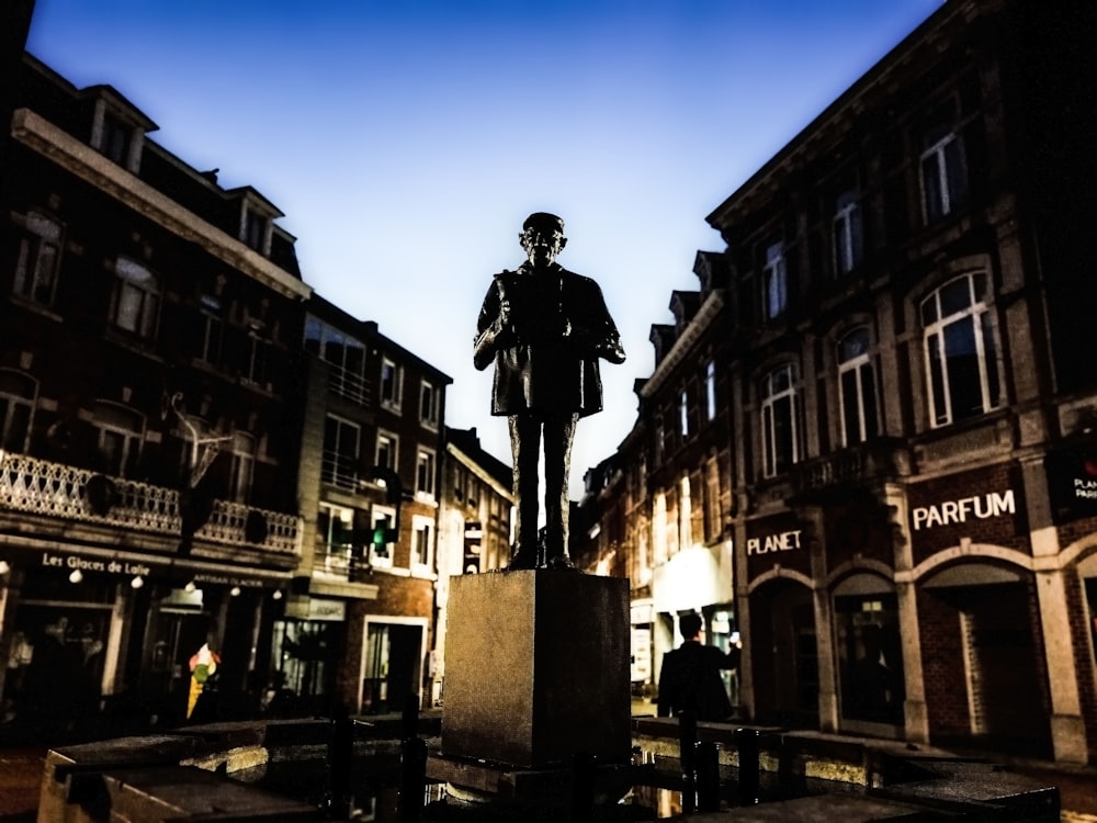 man standing statue in between buildings