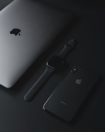 A sleek black iPhone with Apple accessories arranged on a dark, modern background.