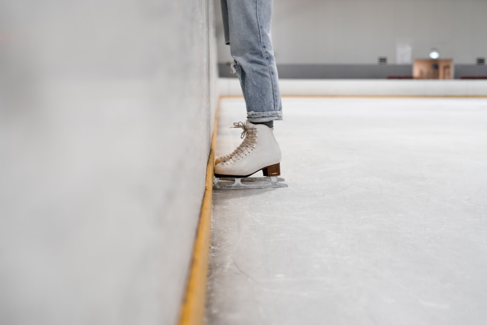 person wearing white and gray skate shoes inside ice skating rink