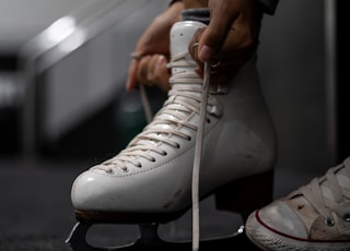 person wearing white leather ice skate