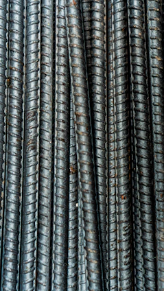 Close-up of a worker inspecting a bundle of steel rebar already showing signs of rust deterioration