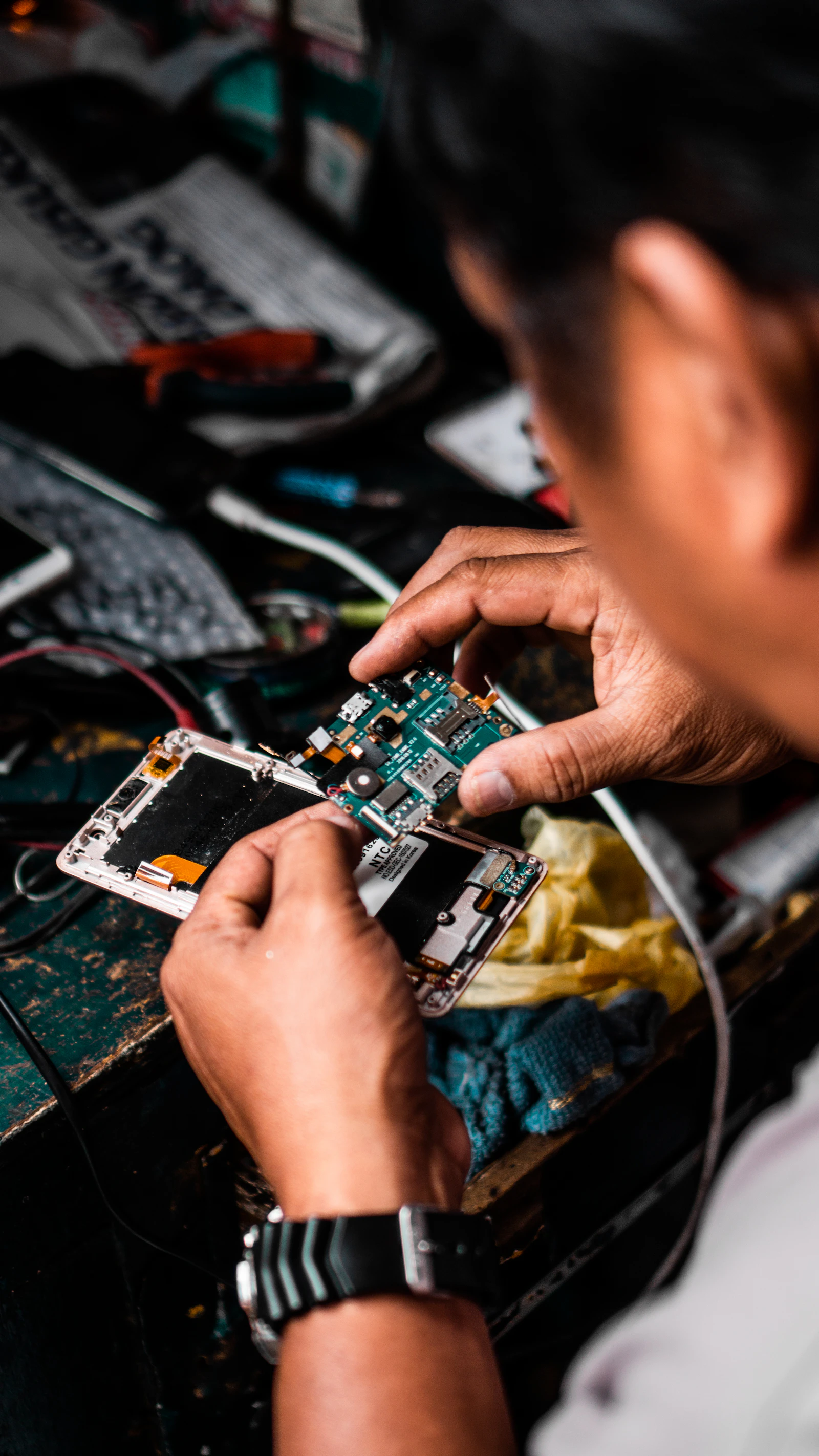 A technician repairing an opened smartphone at a workbench