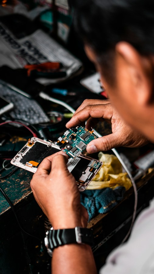 A technician's hands hold a smartphone that has been opened up, its back cover removed to expose the internal circuit board and connectors