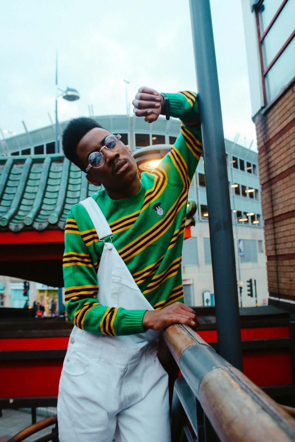 man wearing green, yellow, and white stripe crew-neck sweat shirt with dungarees during daytime