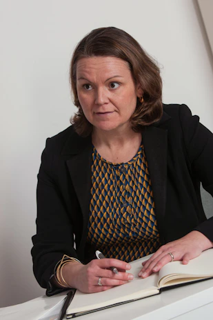 Marieke sitting thoughtfully with a notebook, ready to listen and guide.