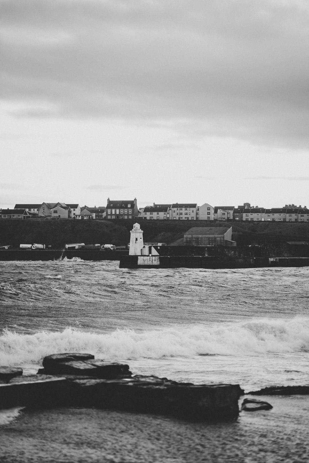 grayscale photography of buildings beside sea waves