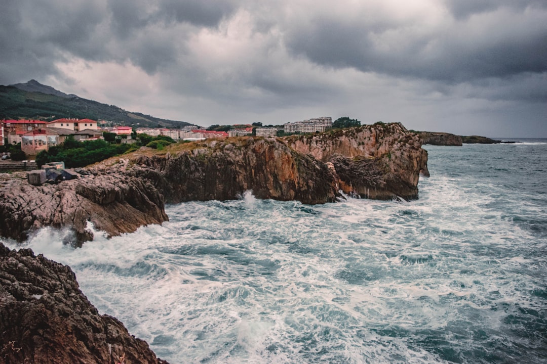 houses beside sea under cloudy sky,