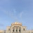 An elegant white building with classical architectural features, adorned with columns and decorative elements, topped with signage that reads 'EMPERADOR'. The sky is clear and blue, providing a serene backdrop.