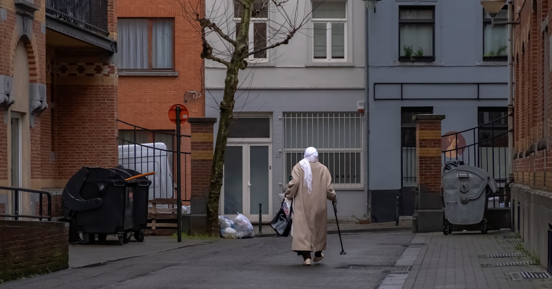 person wearing brown dress walking near gray building