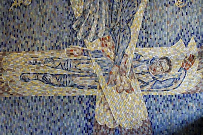 A mosaic artwork depicts an abstract scene with intricate patterns and vivid colors. It features a figure lying down, possibly enveloped or protected. The mosaic is composed of small, colorful tiles arranged to create a dynamic interplay of shapes and lines.