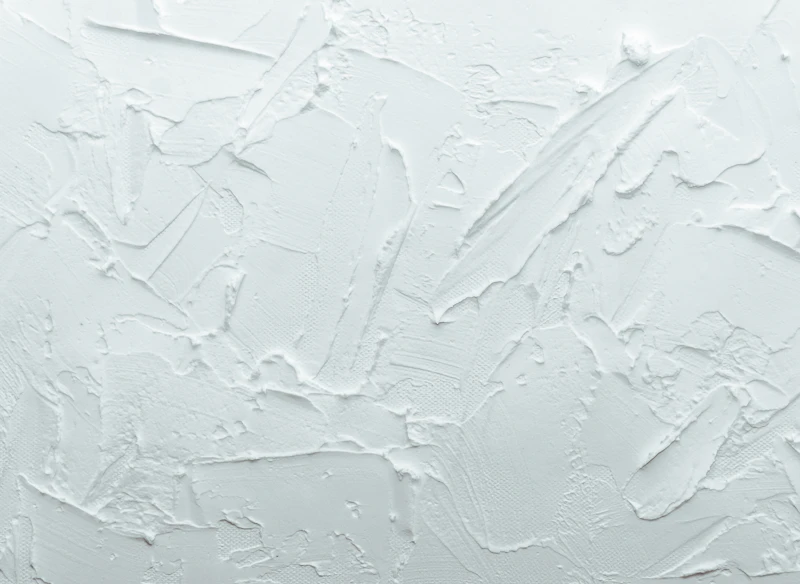 Putty knife filling patches on a white wall, close detail