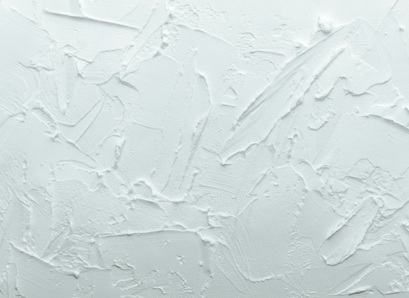 A textured white surface with various overlapping strokes and patterns giving a rough, plaster-like appearance.