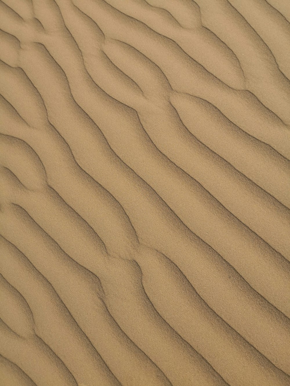 a sand dune with wavy lines in the sand