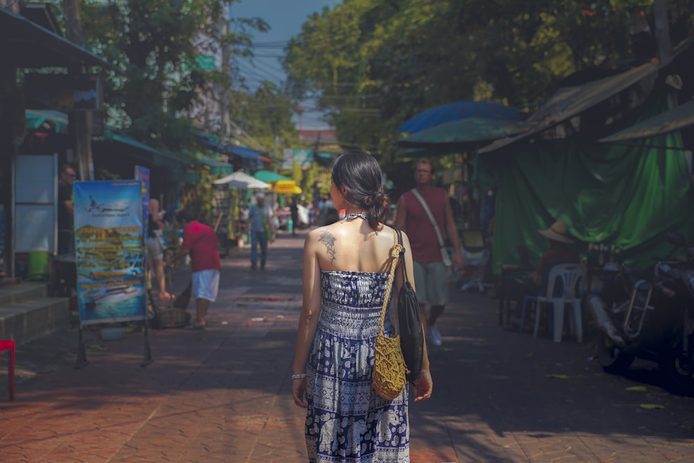 Mujer con vestido largo halter caminando por el camino entre las tiendas