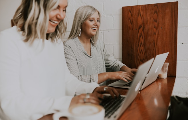 two women using laptops