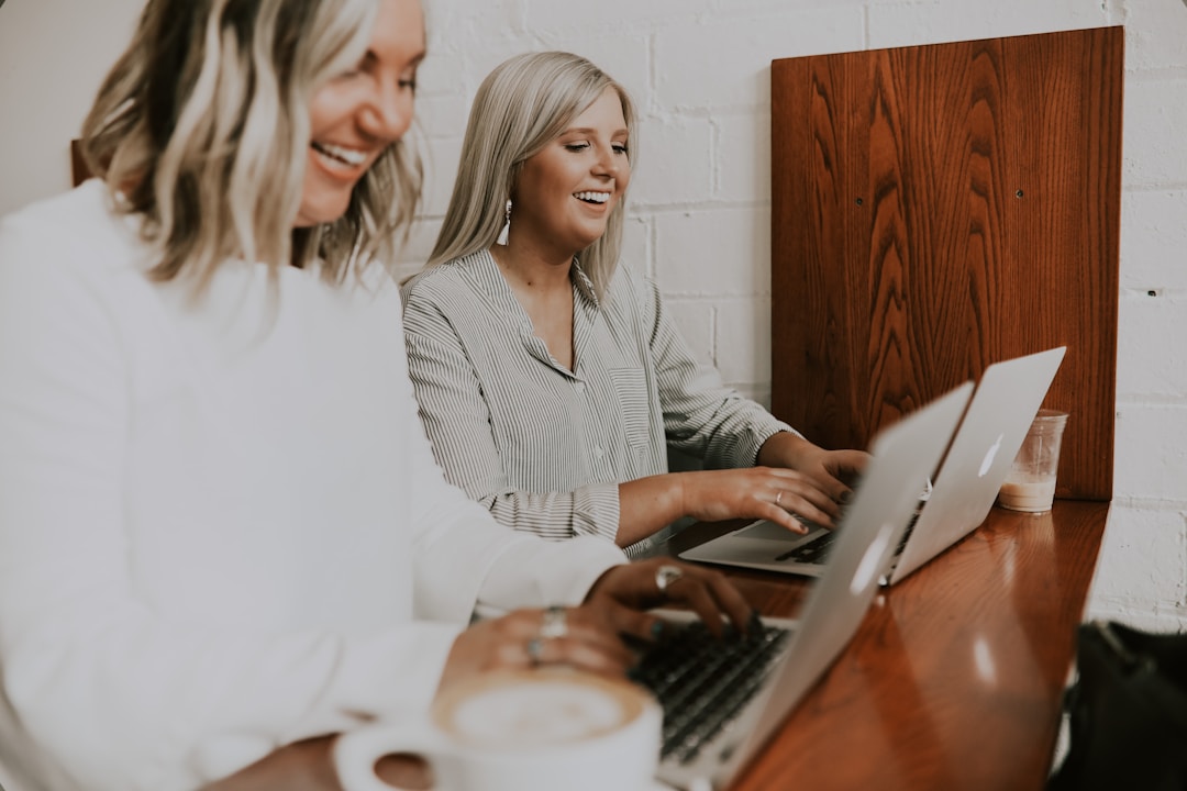 Two professional women collaboratively using a knowledge management system to implement best practices and enhance efficiency.