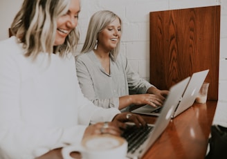 two women using laptops