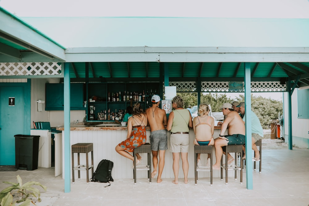 man and woman standing and sitting on bar counter during daytime