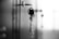 A set of keys is inserted into a lock on a smooth surface, with an Eiffel Tower keychain hanging from the keys. The focus is on the keys and the lock, while the background is softly blurred, creating a shallow depth of field effect. The image is in black and white, emphasizing contrast and light.