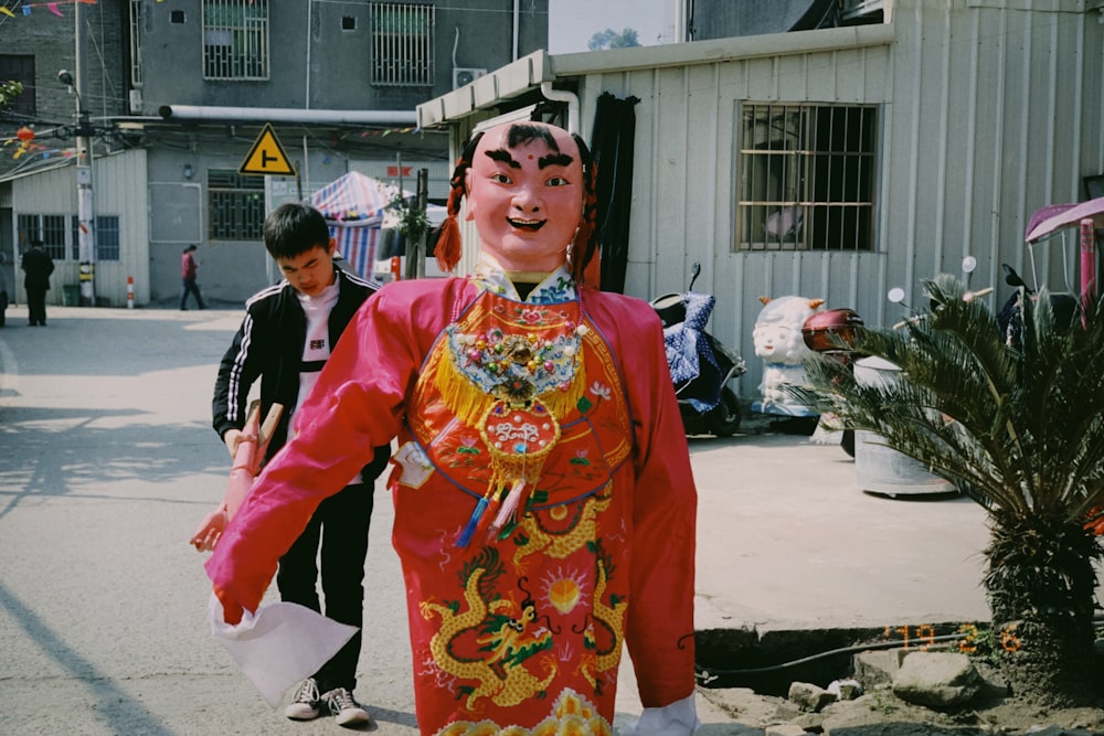 mascot wearing red dress walking near white building