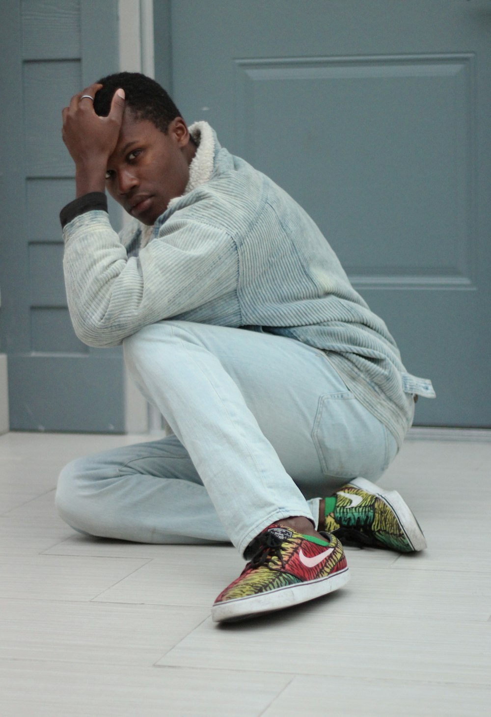 man sitting near gray wooden door