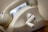 A close-up view of an old rotary dial telephone with a beige, slightly worn surface. The phone features a curved handset resting on top and a manual rotary dial mechanism visible on the side.