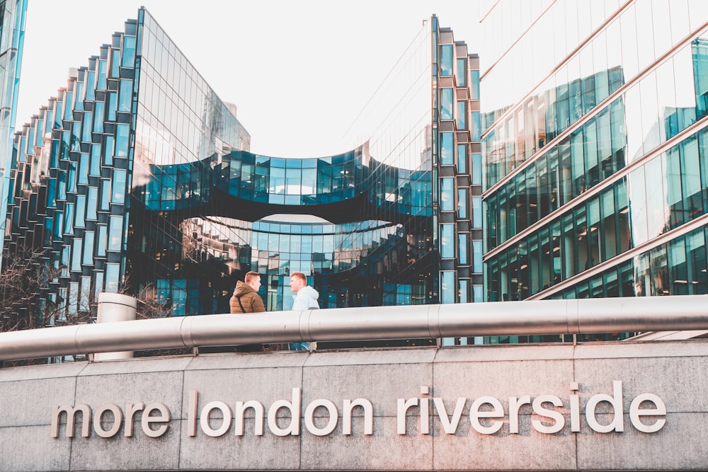 two men leaning on rails with more london riverside sign during daytime