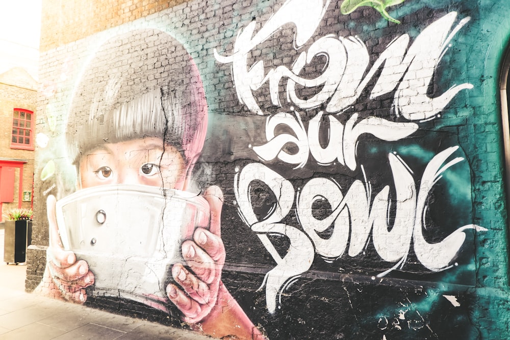 boy holding bowl graffiti wall during daytime